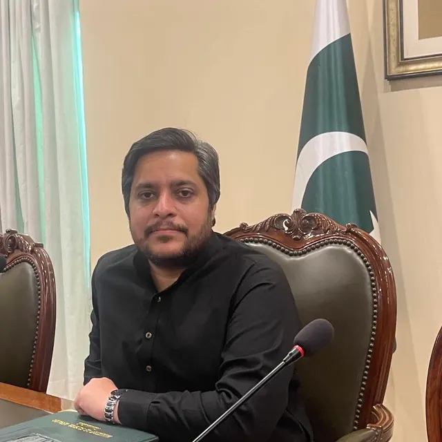 Taimoor Bamazai seated at a desk in front of a Pakistan flag